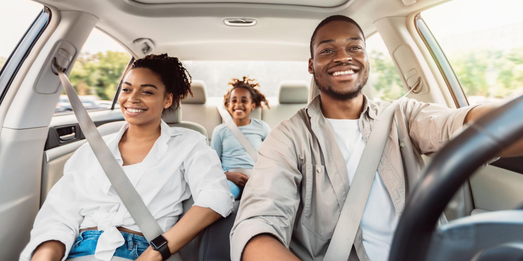Man driving in car with hands on wheel, with woman in passenger seat smiling