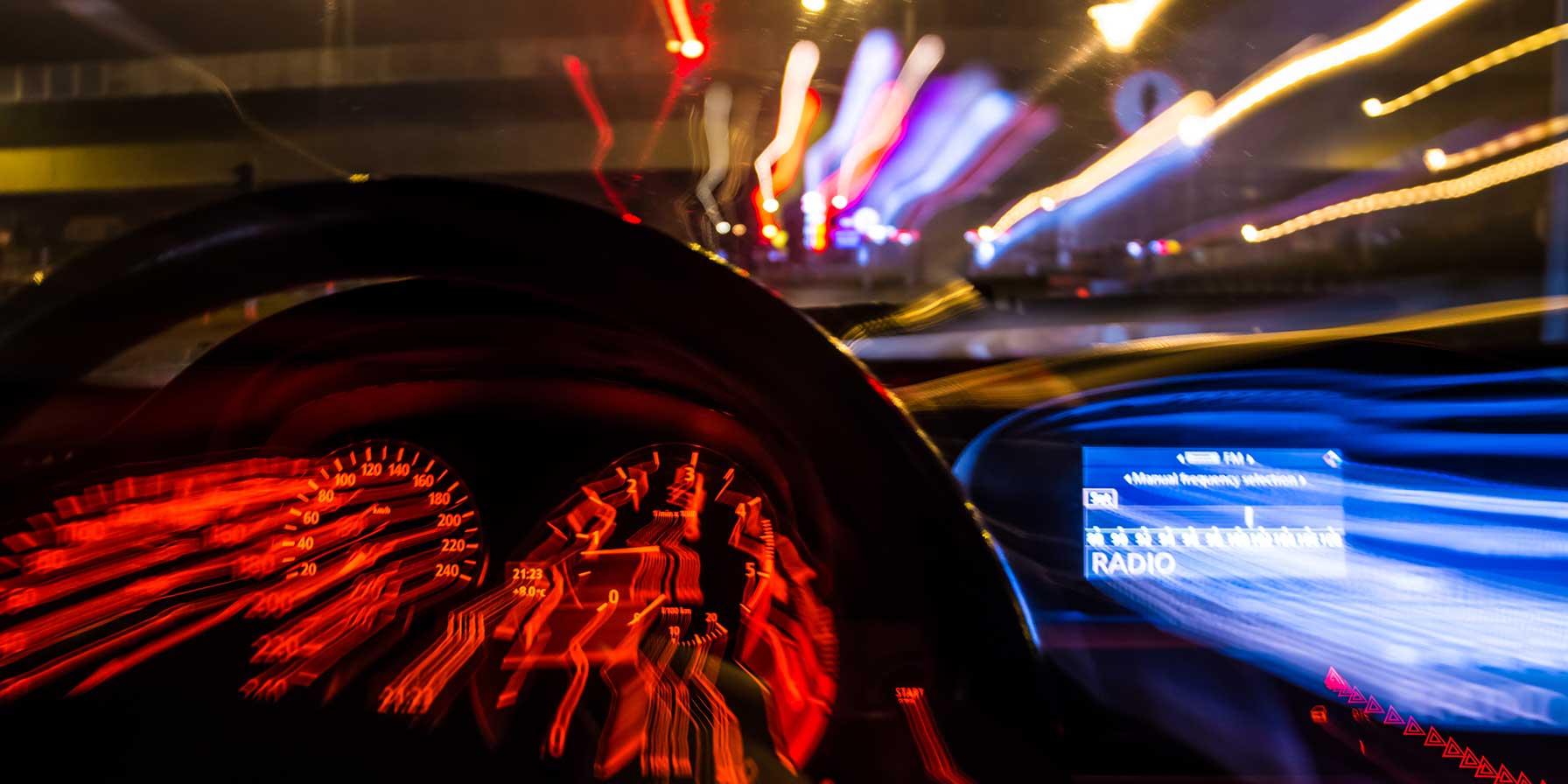 Blurred night view from car with emergency lights ahead.