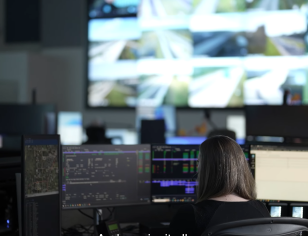 person in customer service center viewing multiple large screens