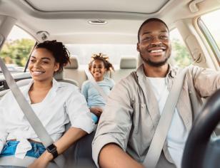 Man driving in car with hands on wheel, with woman in passenger seat smiling