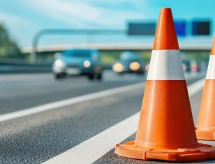 Focus on closeup of orange road cones with cars in background