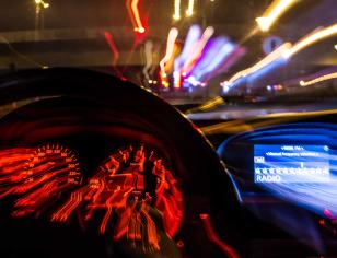 Blurred night view from car with emergency lights ahead.